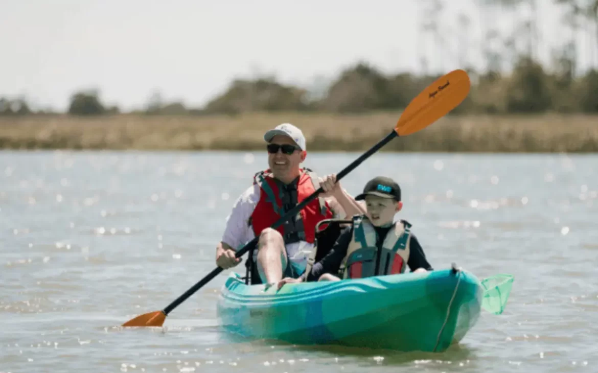 A father and son kayaking on the Kiawah River looking out at nature