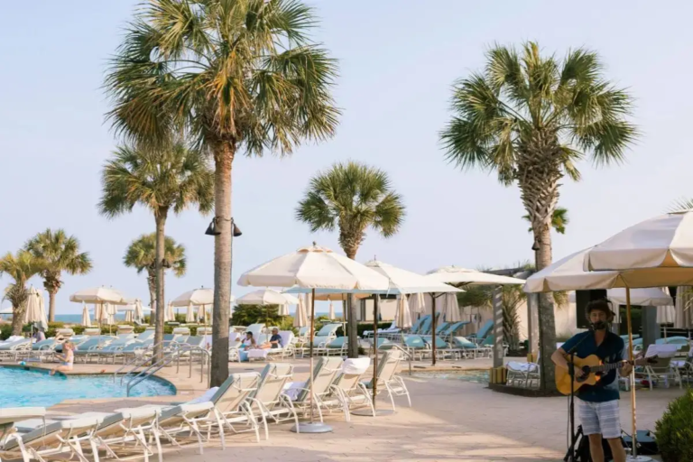 Cover image for the best places to stay on Kiawah Island SC blog which shows a sunny pool deck with palm trees and live music